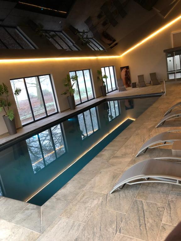 a swimming pool in a room with chairs and windows at Burton Lodge Guest House & Spa in Brandesburton
