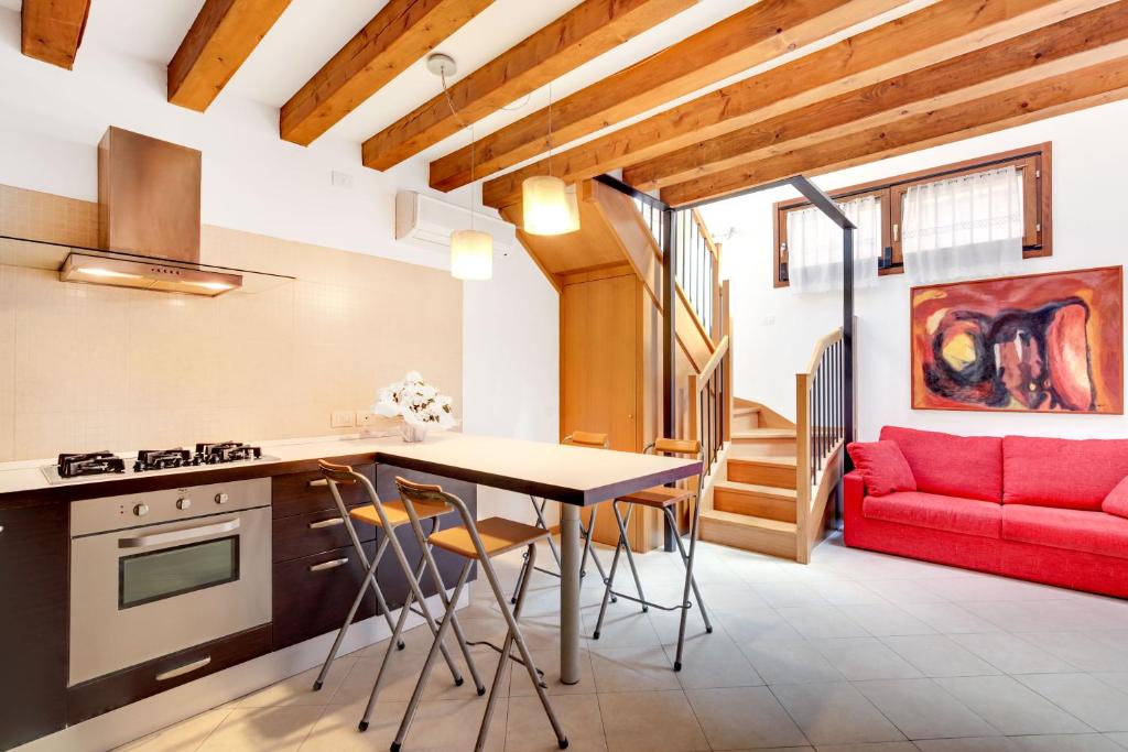 una cucina e un soggiorno con divano rosso di Little Canal 14 a Venezia