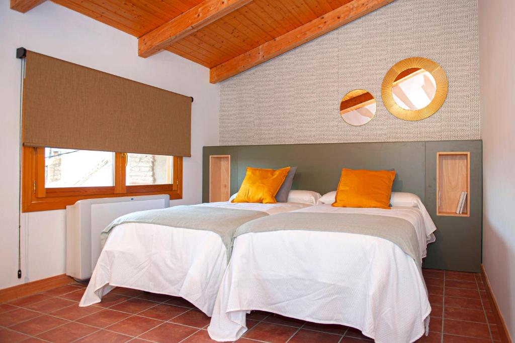 TorrellesにあるCasa Rural Hospital de las Palabrasのベッドルーム1室(白とオレンジの枕が備わるベッド2台付)
