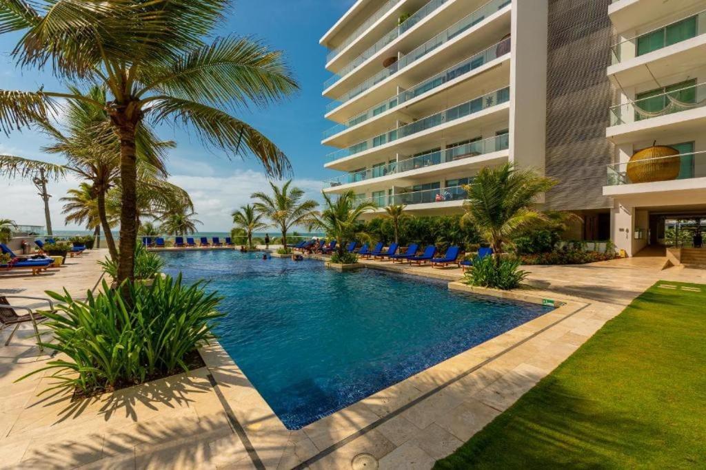 ein Resortpool mit Palmen und ein Gebäude in der Unterkunft Apartamento en Condominio con Salida al Mar MORROS EPIC in Cartagena de Indias