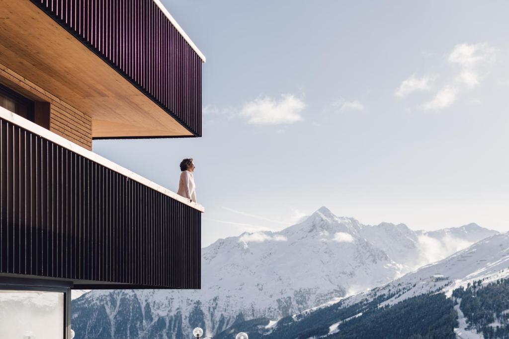 una persona parada en un balcón con vistas a las montañas en Hotel Schöne Aussicht en Sölden