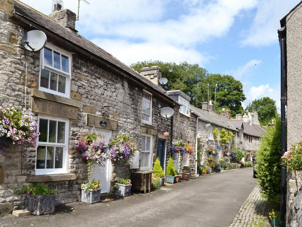 Une rangée de maisons en pierre avec des fleurs sur elles dans l'établissement Ash Cottage, à Tideswell