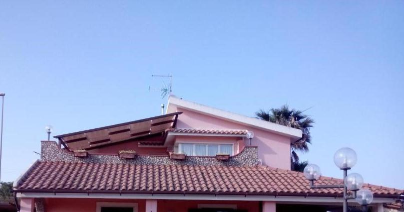 a pink house with a palm tree behind it at Appartamento Ognina Siracusa in Ognina