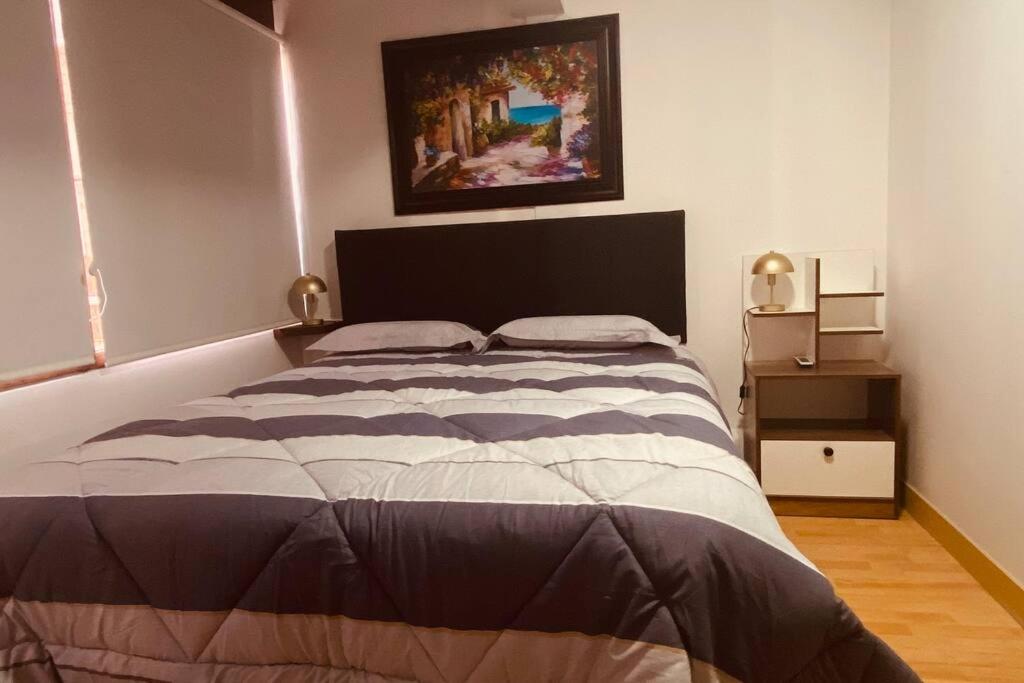 1 dormitorio con 1 cama con una foto en la pared en (27) Acogedor Dpto en Miraflores, en Lima