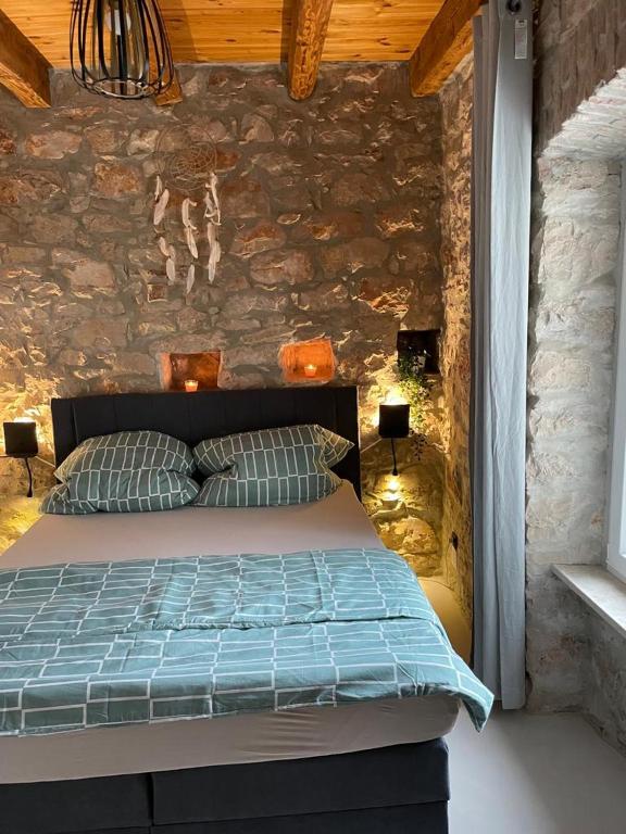 sypialnia z łóżkiem i kamienną ścianą w obiekcie Villa Makale w mieście Umag
