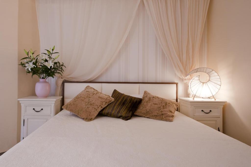 a bedroom with a white bed with two white night stands at Polydor in Tolo