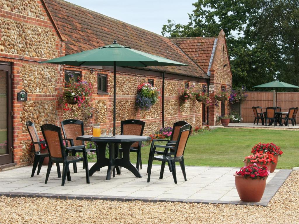 a patio with a table and chairs and an umbrella at Littlewood Barn - Ukc3737 in Bawdeswell