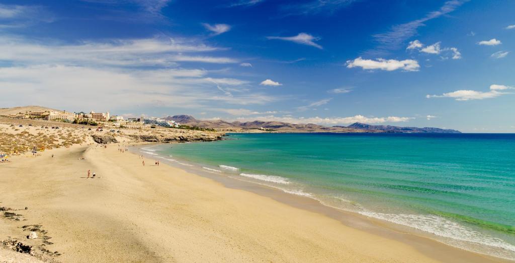 a beach with people on the sand and the water at H10 Playa Esmeralda - Adults Only in Costa Calma