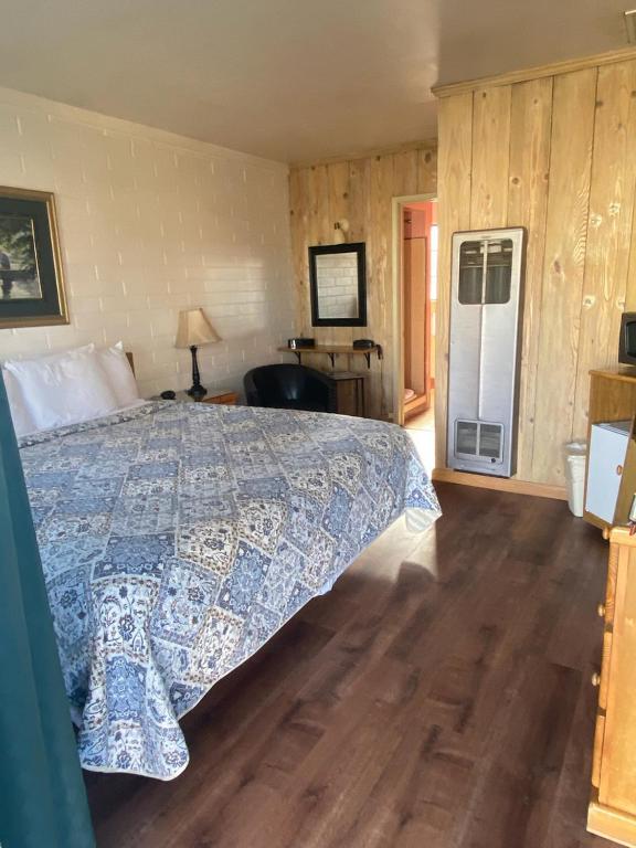 a bedroom with a bed with a blue and white bedspread at Bishop Village Motel in Bishop