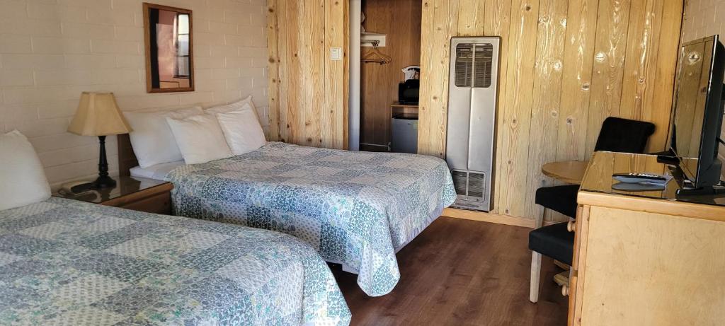 a hotel room with two beds and a television at Bishop Village Motel in Bishop