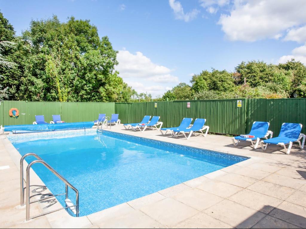 a swimming pool with blue chairs and a fence at Discovery in Cheriton Bishop