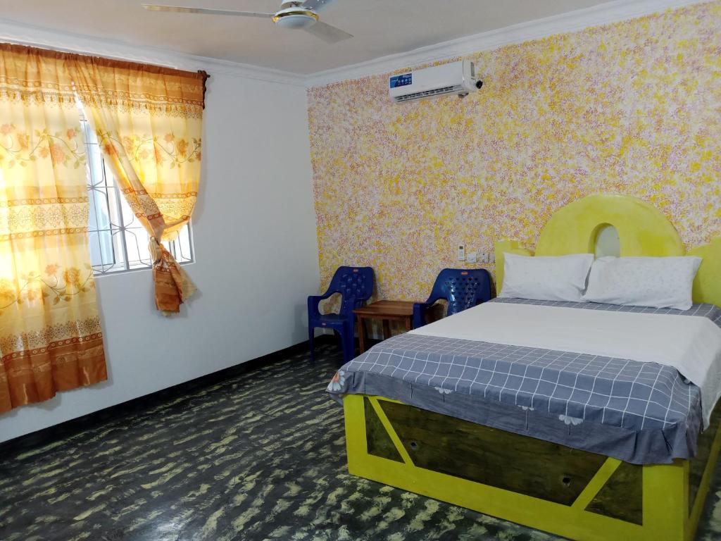 a bedroom with a bed and chairs and a window at Ndiro Beach House Kendwa in Kendwa