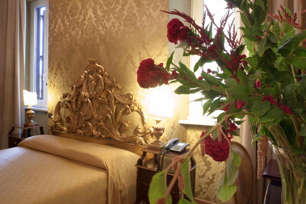 ein Schlafzimmer mit einem Bett mit Blumenarrangement daneben in der Unterkunft Hotel Des Epoques in Rom