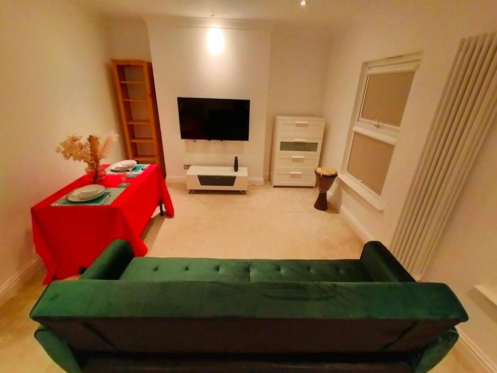 salon z zieloną kanapą i czerwonym stołem w obiekcie Fully-equipped flat in the city of London. w Londynie