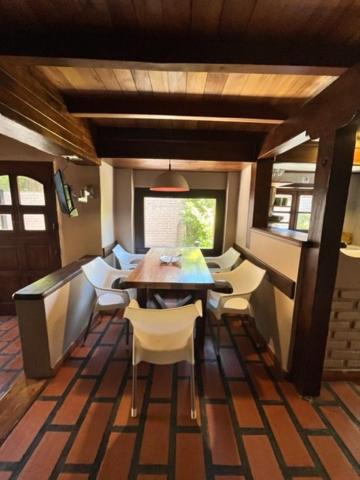 a dining room with a table and white chairs at Casita de Villegas in San Martín de los Andes