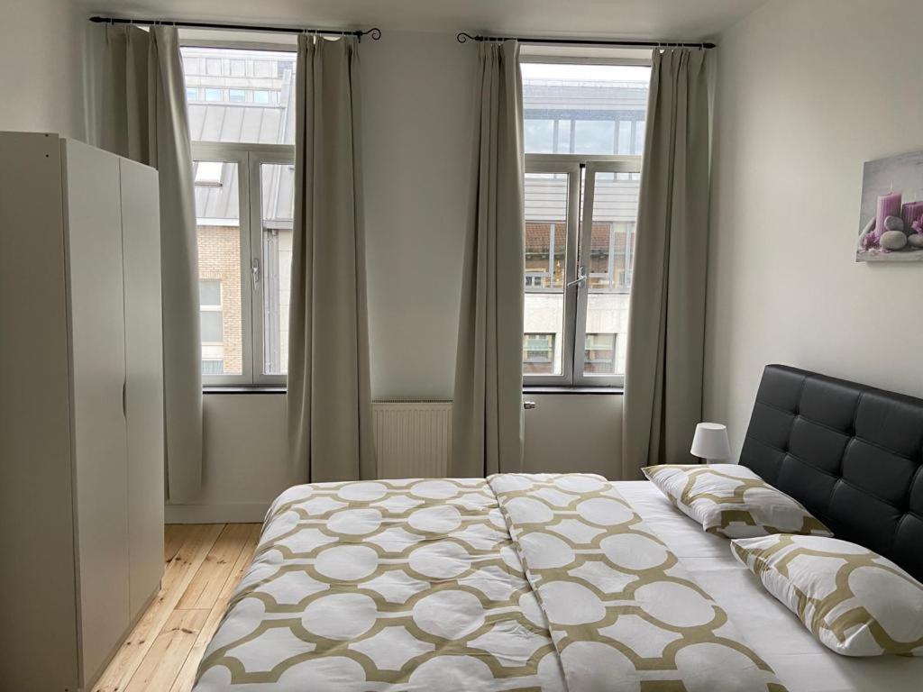 een slaapkamer met een groot bed en 2 ramen bij Modern Apartment Third Floor in Brussel