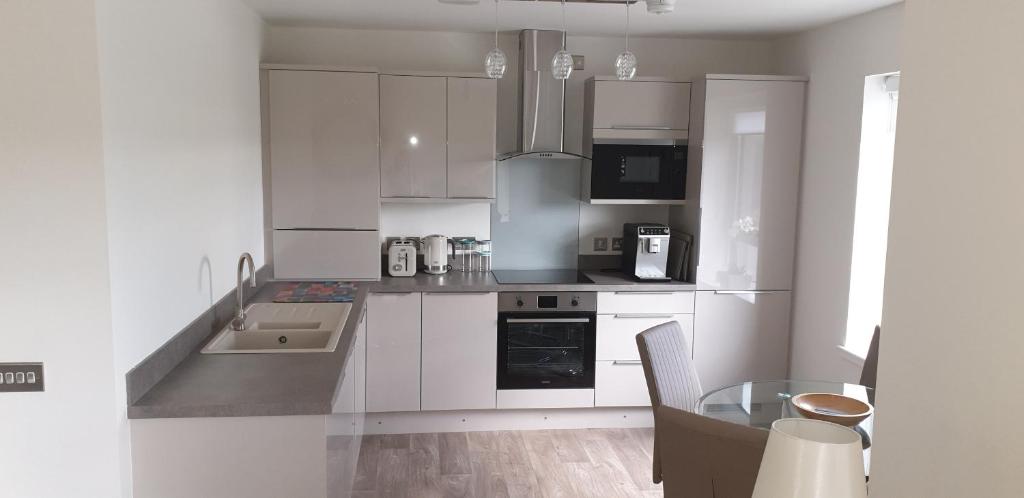 cocina con armarios blancos y mesa de cristal en Luxurious First Floor Flat en Dornoch