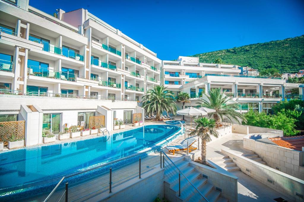 a swimming pool in front of a large building at Monte Casa SPA & Wellness in Petrovac na Moru