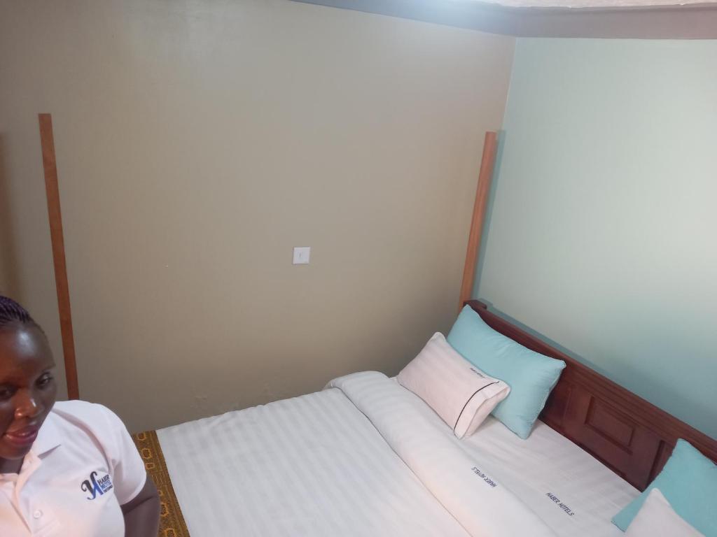 een vrouw in een kleine kamer met twee bedden bij Habermotel Enterprise Ltd in Entebbe