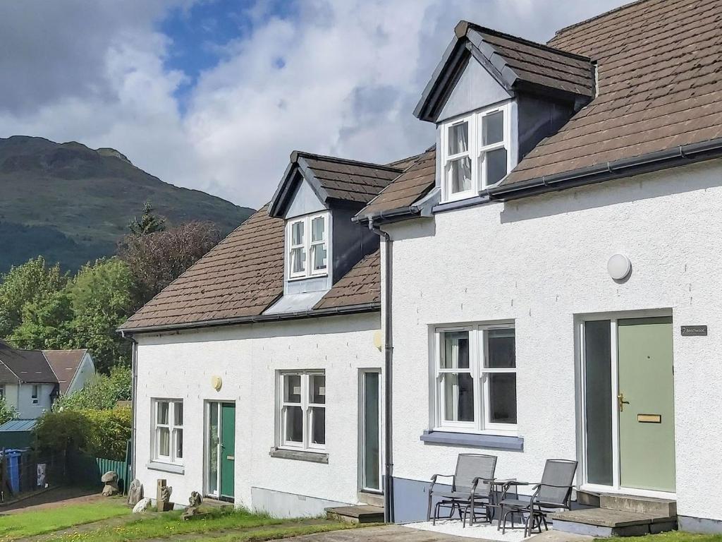 a white house with a table and chairs in front of it at Beechwood in Arrochar