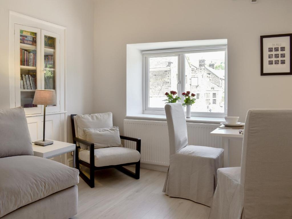 ein Wohnzimmer mit einem Sofa, einem Stuhl und einem Fenster in der Unterkunft Morton Loft in Hathersage