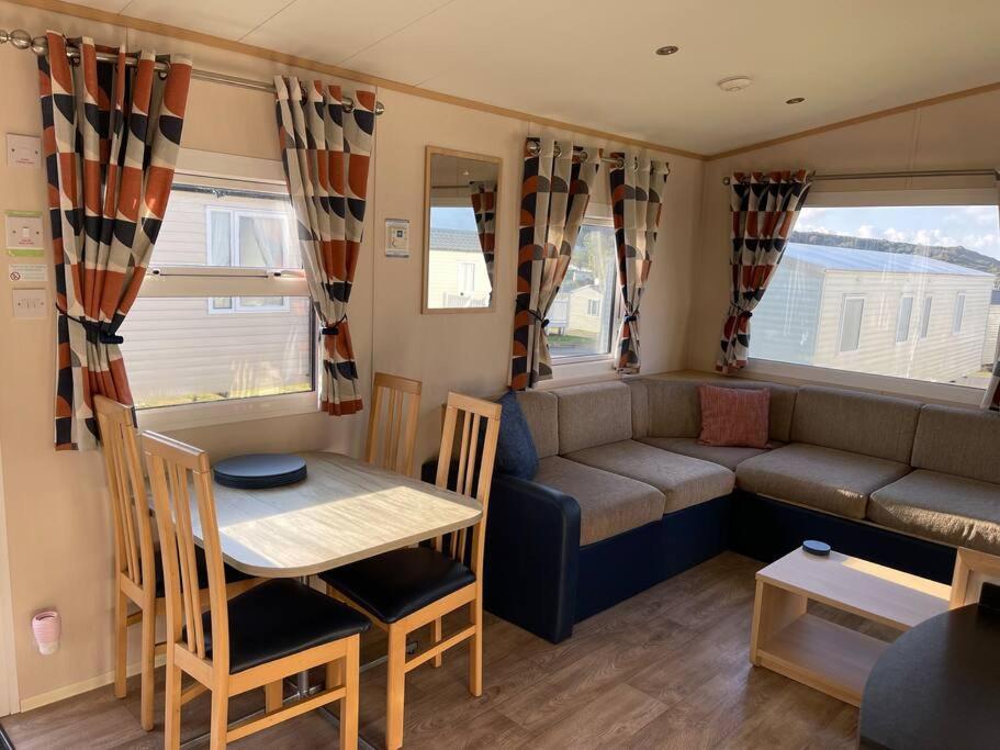a caravan living room with a table and a couch at Lexi Lodge @ Littlesea Holiday Park, Weymouth in Wyke Regis
