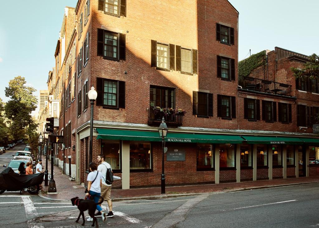 a group of people walking a dog on a city street at Beacon Hill Hotel in Boston