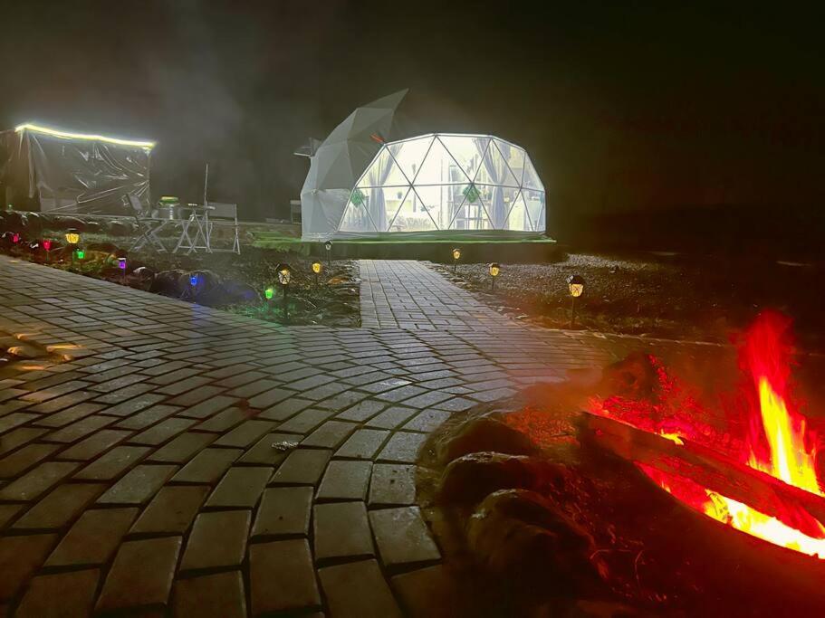 a fire pit with a building in the background at night at Heart Of The Hills in Golan Heights