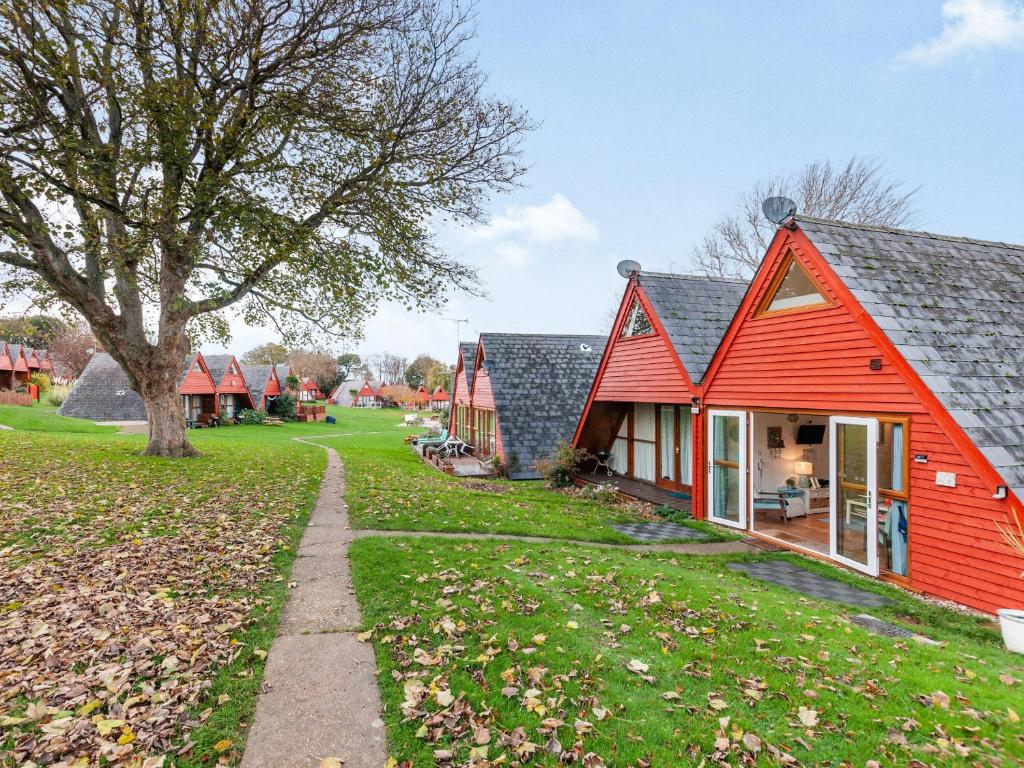 a row of red cottages with a tree at Chalet 56 in Kingsdown