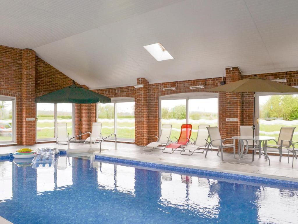 a swimming pool with chairs and tables and umbrellas at Koi Keep - Ukc1909 in Doddington