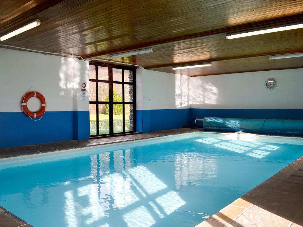 uma piscina com água azul num edifício em Robins Retreat - Uk6548 em Llanfihangel-Bryn-Pabuan