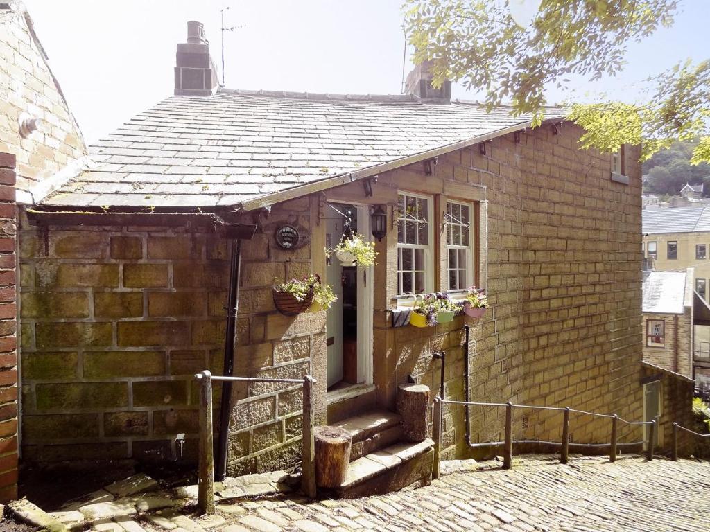 ein kleines Backsteinhaus mit einer Tür und einer Treppe in der Unterkunft Birkenhead Cottage in Hebden Bridge