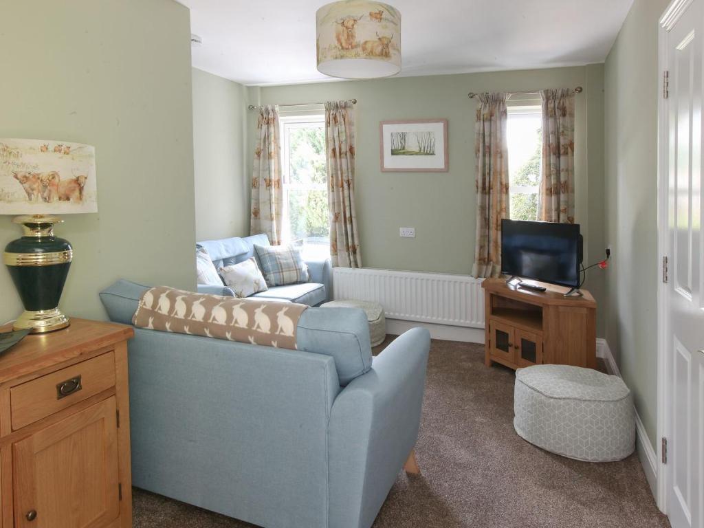 a living room with a blue couch and a tv at Netherwood in Bakewell