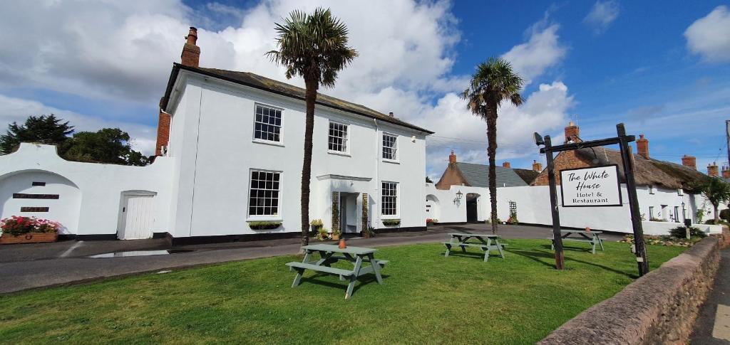 a white building with two picnic tables in front of it at The White House Guest House in Williton