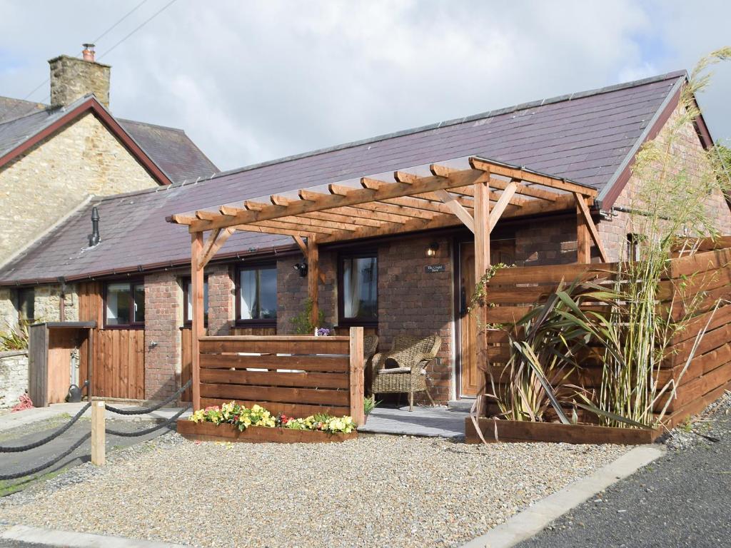 a house with a wooden pergola in front of it at The Chapel Barn in Llangynllo