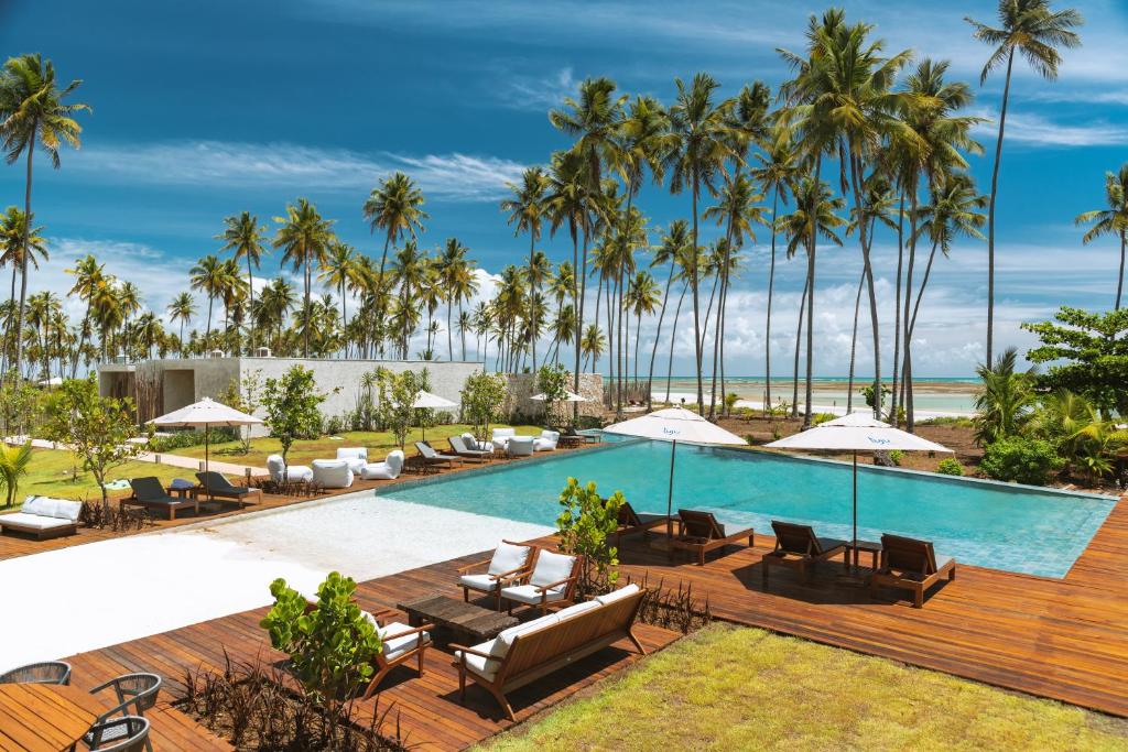 - une piscine avec des chaises longues et des palmiers dans l'établissement Tuju Boutique Hotel, à Passo de Camarajibe