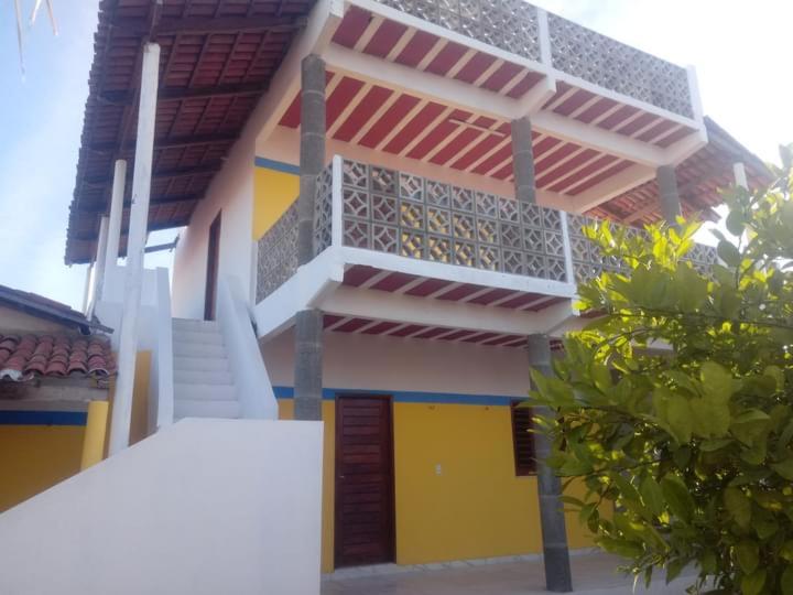 un edificio giallo e bianco con scale di fronte di Dunas Bar&Hotel a Canoa Quebrada