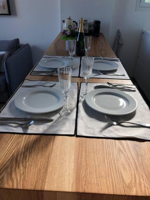 a wooden table with plates and forks and glasses at Belle vue sur mer, très près du port de Sanary in Sanary-sur-Mer