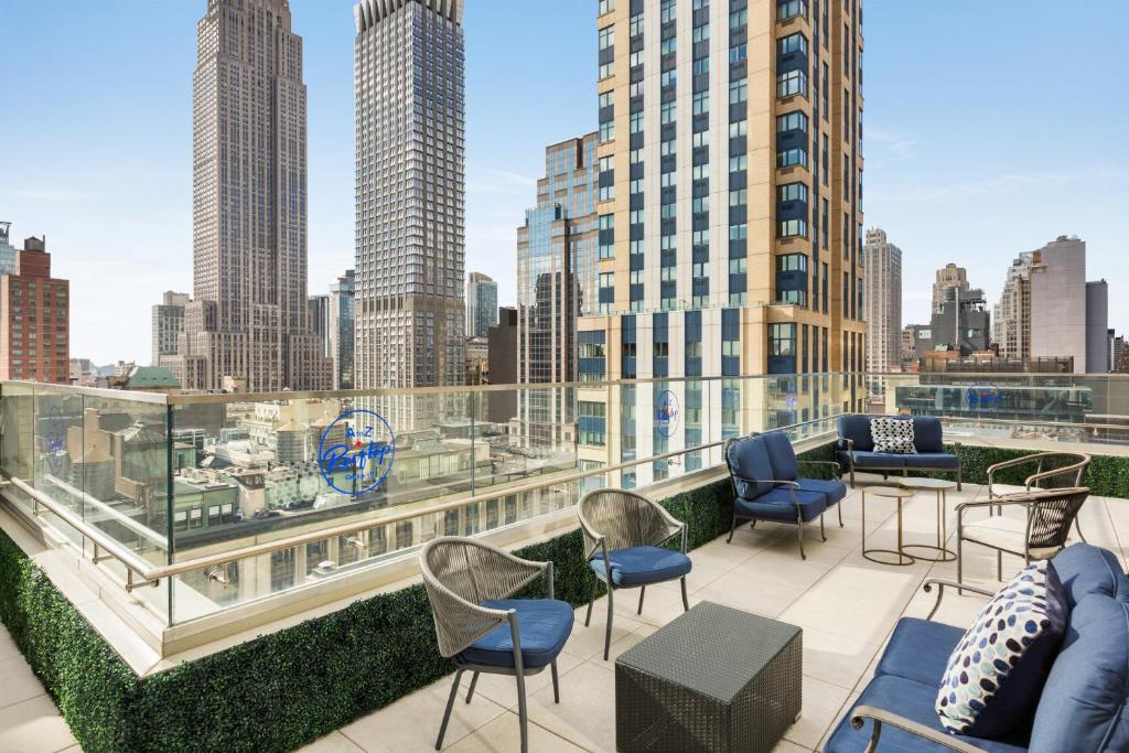 Hyatt Centric Midtown 5th Avenue New York في نيويورك: فناء على السطح مع كراسي وطاولات وإطلالة على المدينة