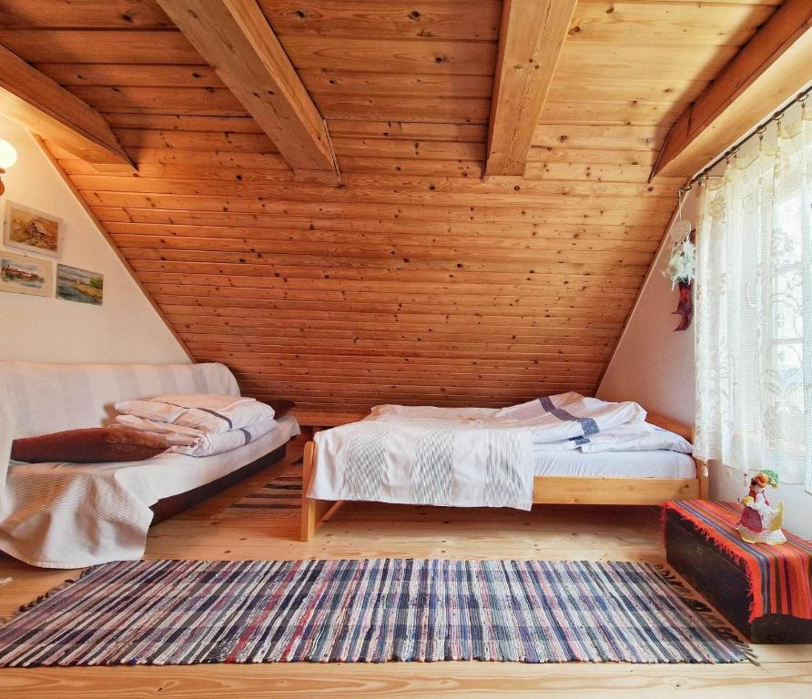 a bedroom with two beds and a wooden ceiling at Góralska Chata Bystre z 1863r in Istebna