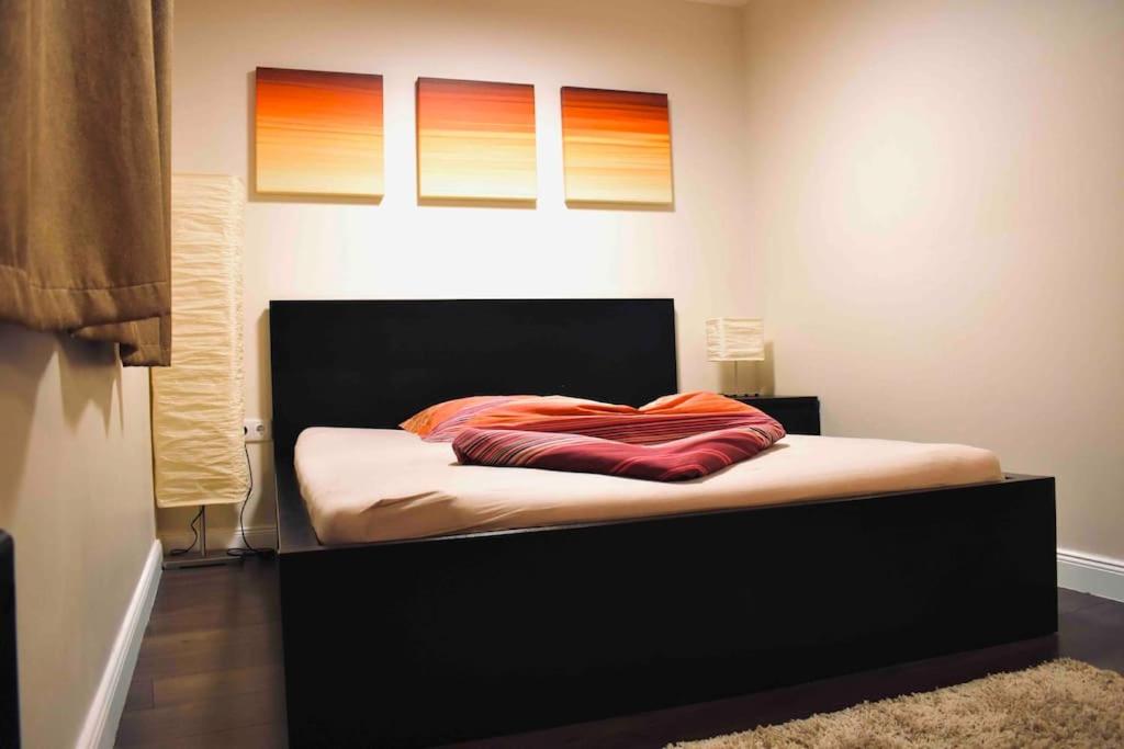 Una cama con cabecero negro y almohadas naranjas. en Premium Casa Apartman en Sopron