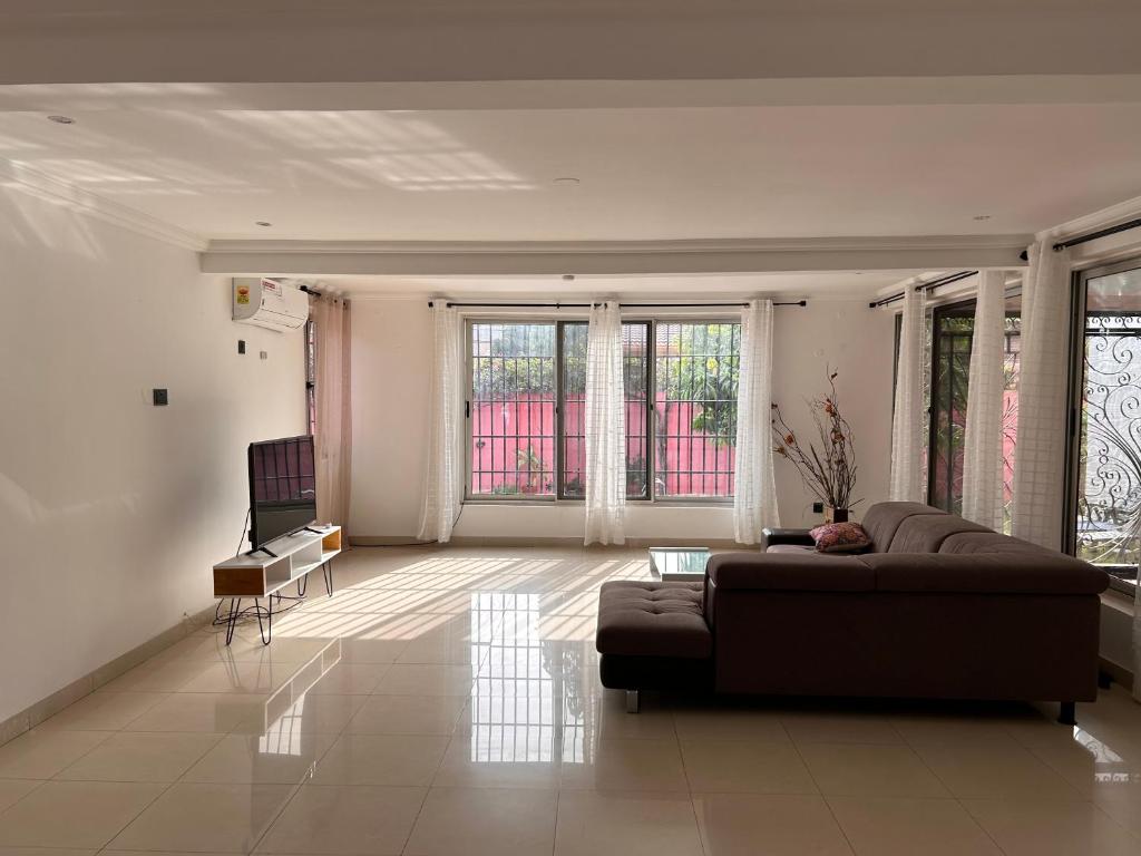 a living room with a couch and some windows at The Dzorwulu Castle - A Villa with private rooms in Accra