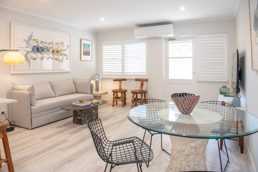 a living room with a glass table and chairs at Luxury modern CBD ground floor apartment. in Canberra