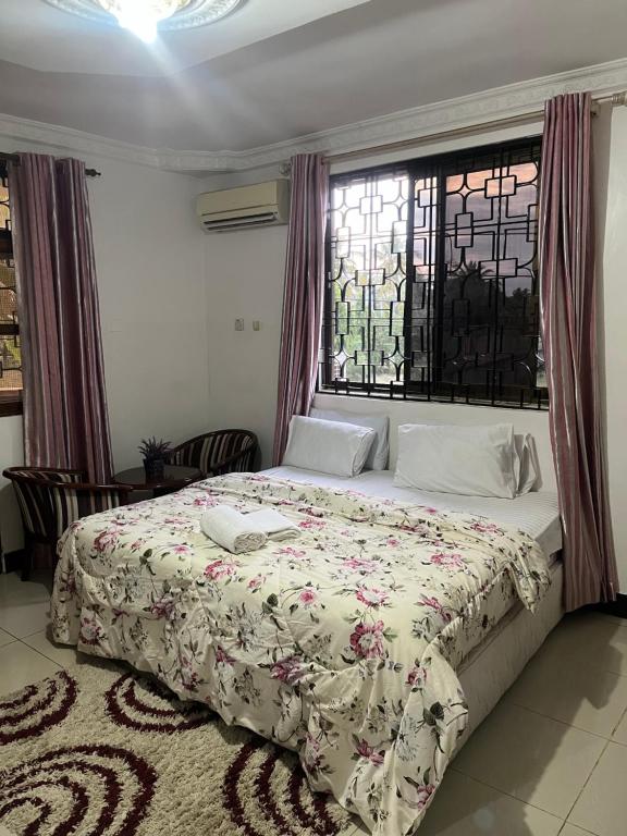 um quarto com uma cama grande e uma janela em Stay In Style Lodge em Dar es Salaam