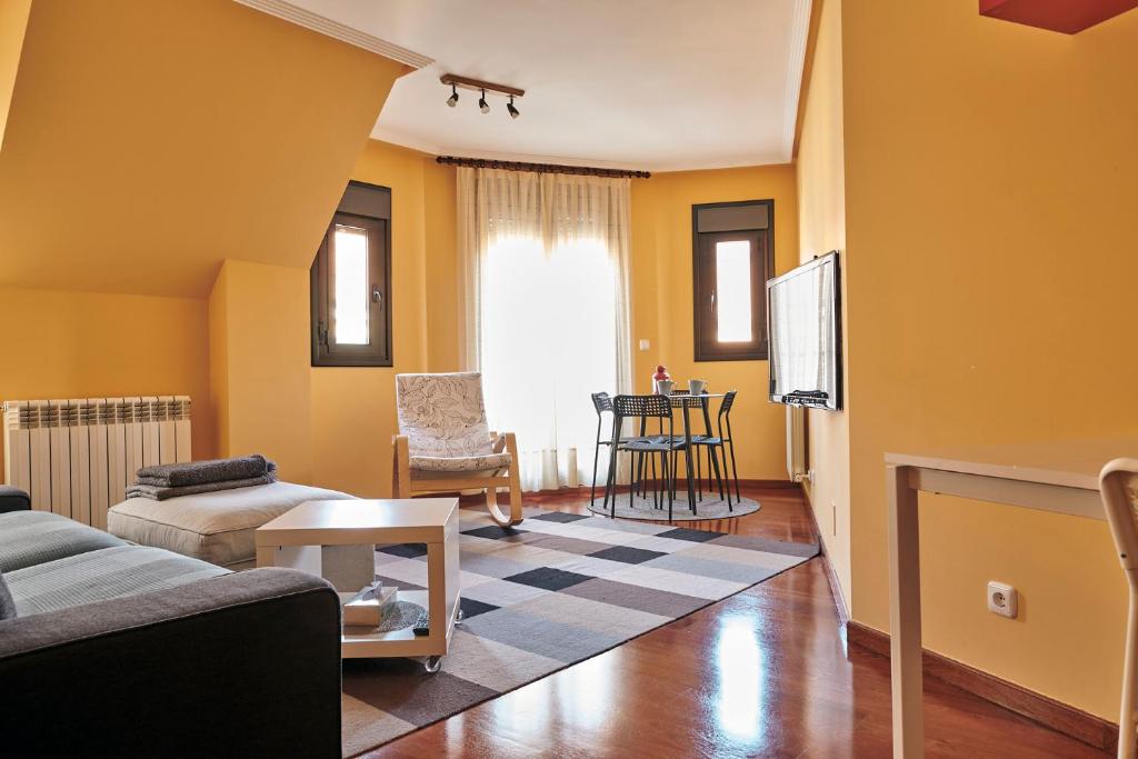 a living room with yellow walls and a couch and a tv at Apartamento La Calma, plaza de La Inmaculada, en el centro de León in León