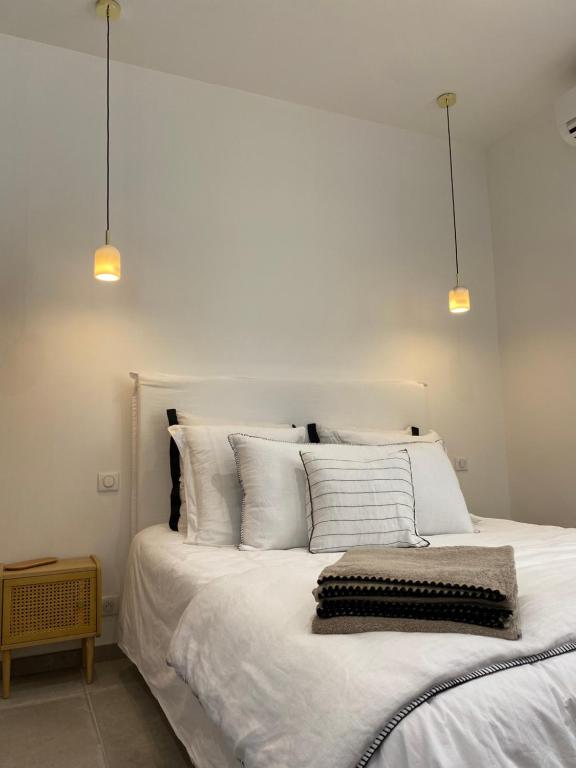 a bedroom with a white bed with three pillows at Belle vue sur mer, très près du port de Sanary in Sanary-sur-Mer