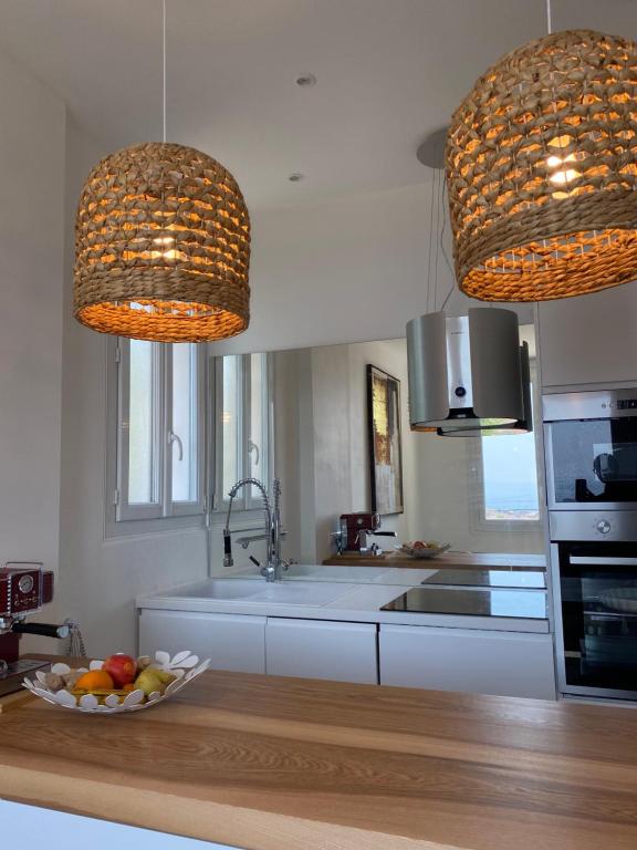 a kitchen with two hanging lights and a bowl of fruit at Belle vue sur mer, très près du port de Sanary in Sanary-sur-Mer