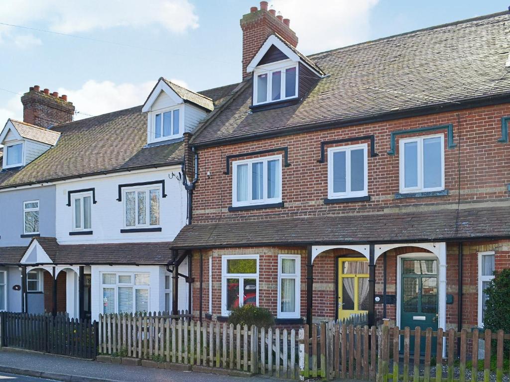 a brick house with white windows and a fence at The Castaway in Mundesley