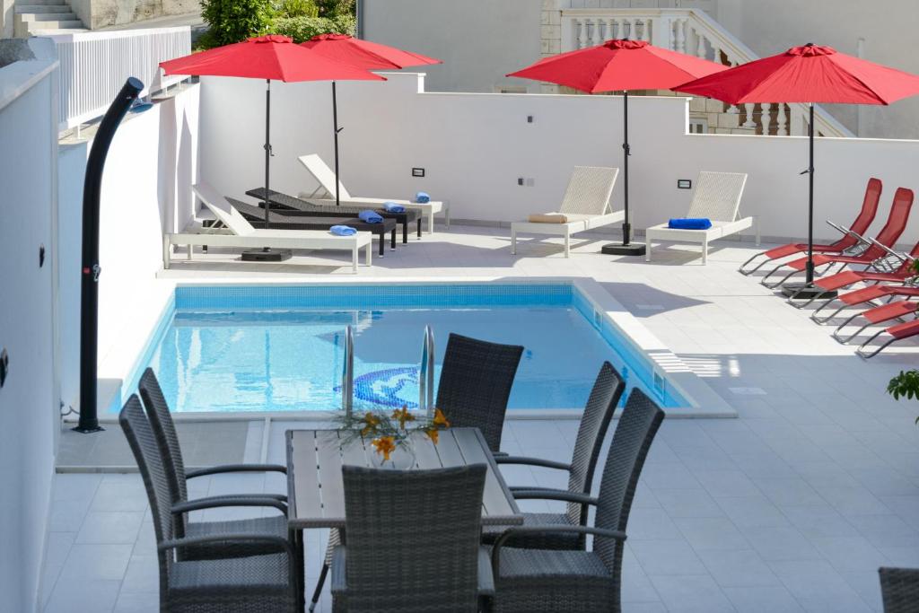 una piscina con sillas, mesas y sombrillas en Villa Bingo, en Cavtat