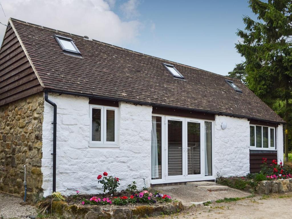 a white cottage with a brown roof at Cornbrash Farm Cottage in Dallington